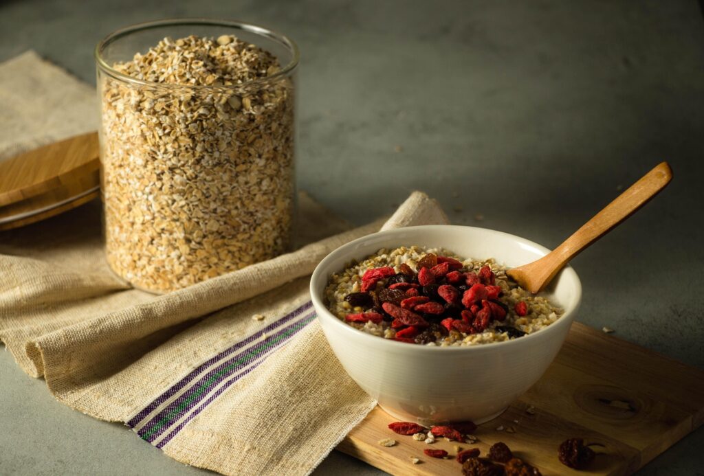 Bol de avena con bayas goji y pasas junto a un tarro de copos de avena, desayuno energético para surfistas