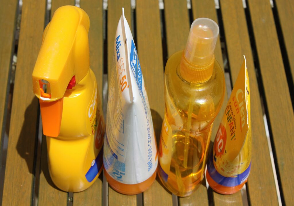 Varios productos de protección solar en spray y crema con factor SPF 50 sobre una superficie de madera