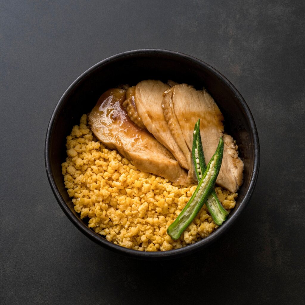 Bol negro con pollo a la plancha con salsa teriyaki, bulgur y judías verdes, comida de recuperación post-sesión de surf